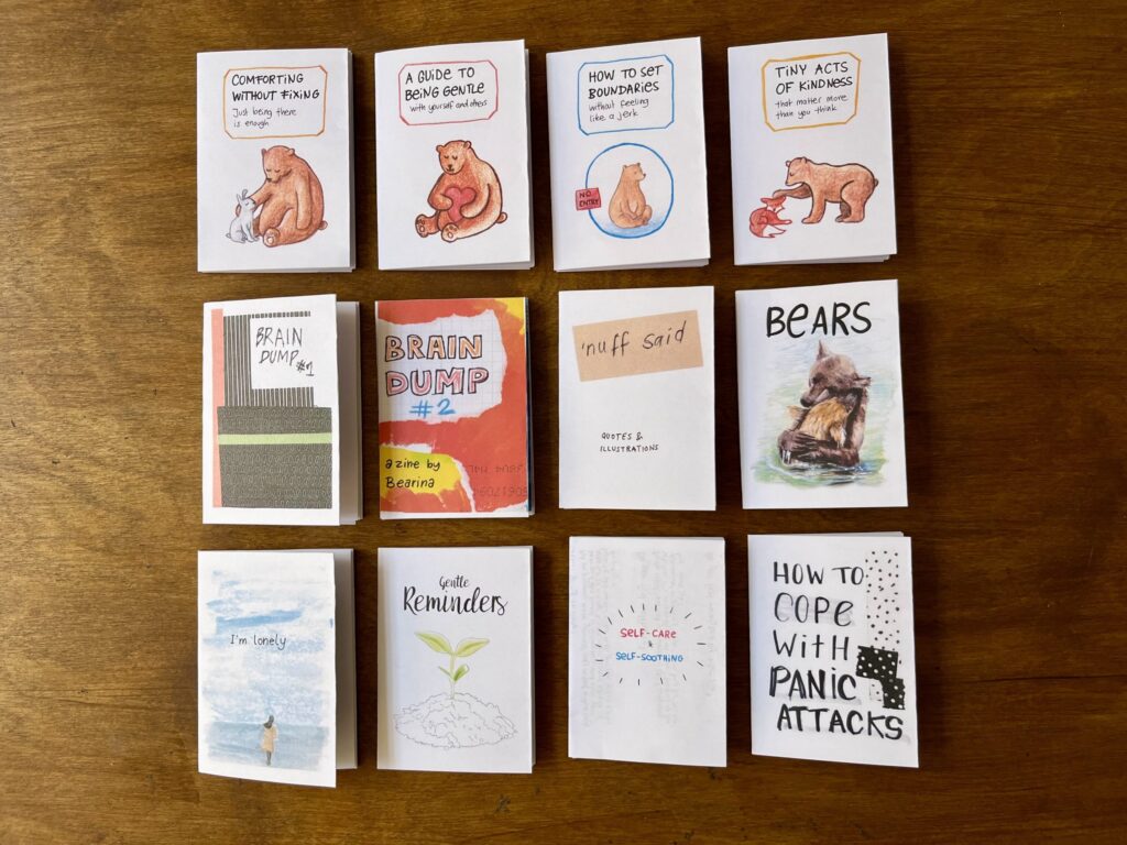 Im Foto liegen zwölf Mini-Zines von "Bearina" in drei Reihen á vier Zines.